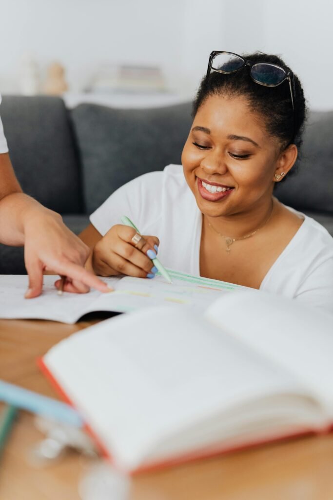 A smiling woman studying with a tutor, highlighting learning and education.